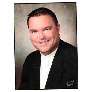Dr. Brian Bak, D.C., in a jacket and white shirt, smiling